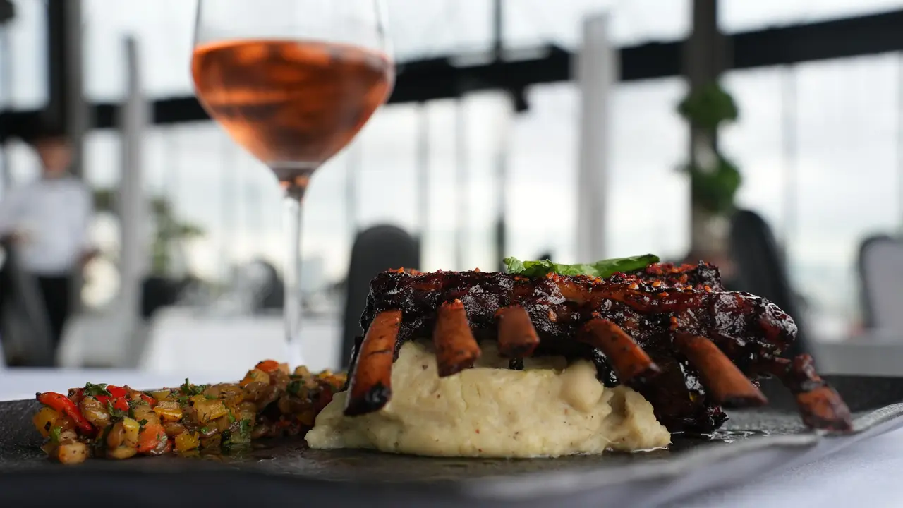 Glazed lamb ribs on mashed potato with a glass of rosé